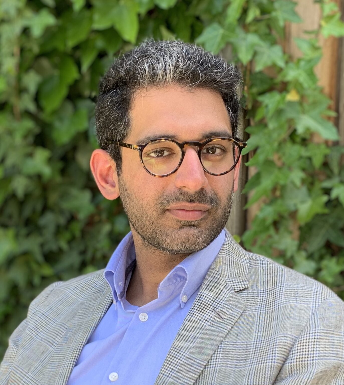 A portrait of a person against green foliage.