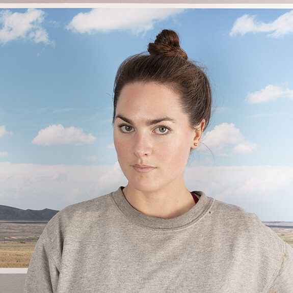 A portrait of a person in front of a photograph.