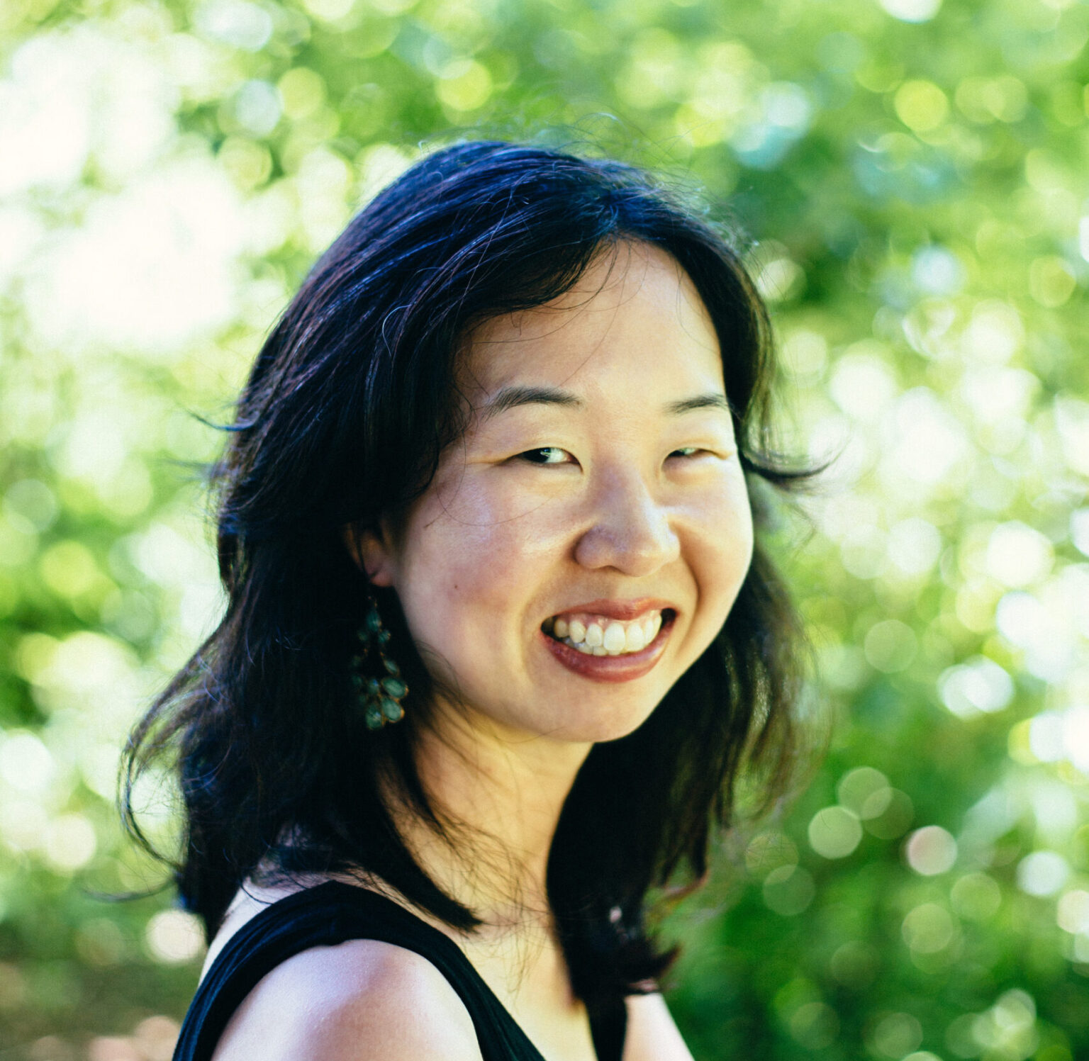 A portrait of a person against green foliage.