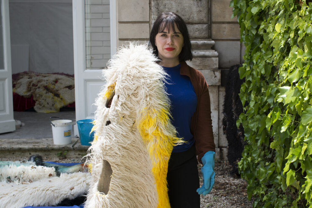 A person holding a pelt that has been partially painted yellow.