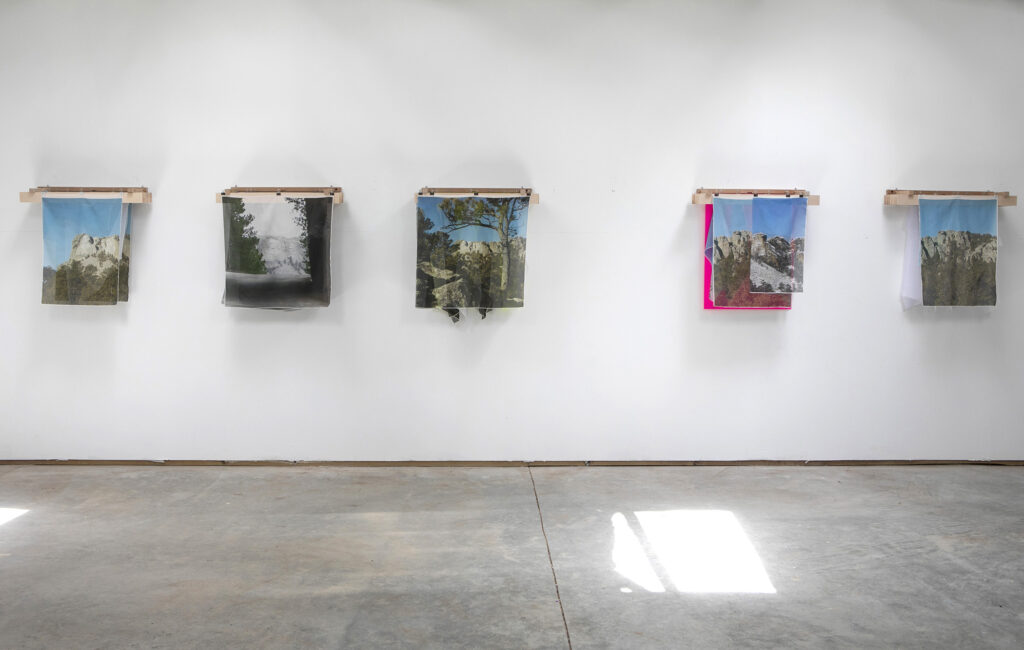 Five layered works hanging on a wall