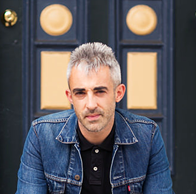 A portrait of a person in front of a painted door.