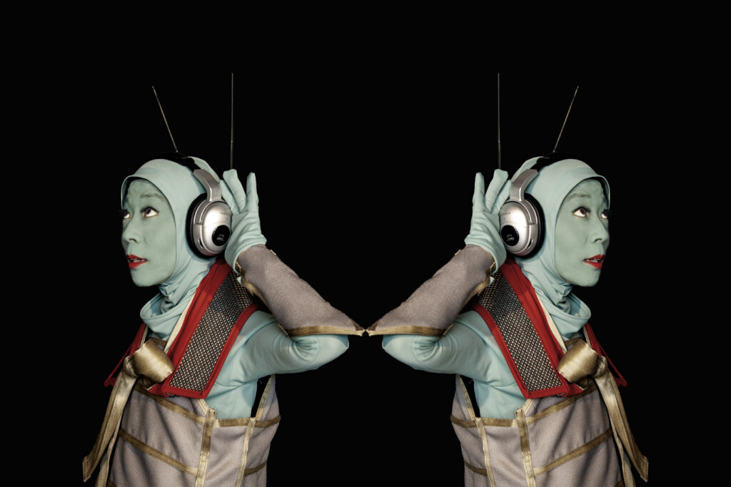 A mirrored image of a person in a costume listening to headphones.