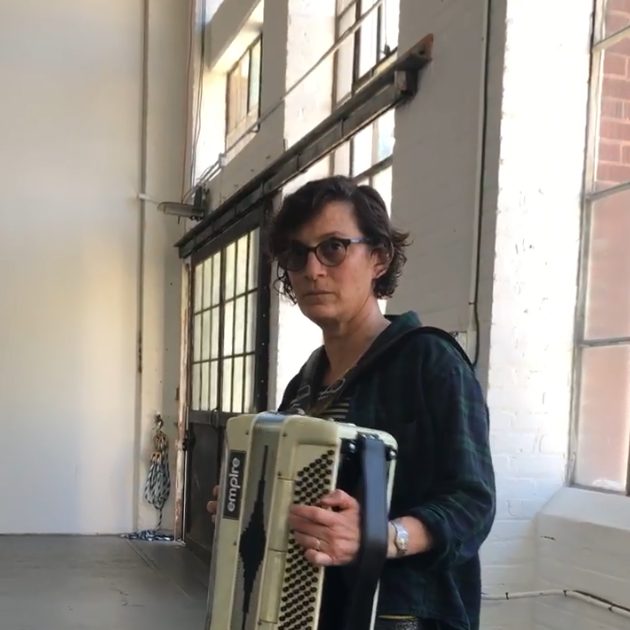 A person standing in a room holding an accordion.