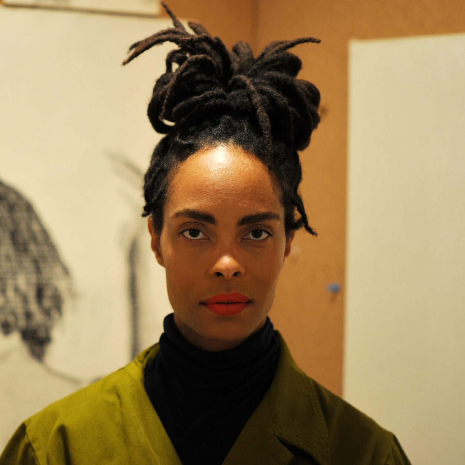 A portrait of a person in front of an artwork.