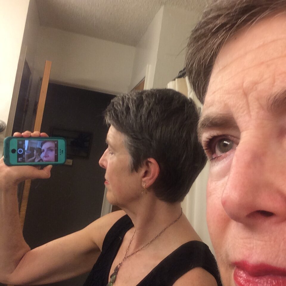 A close-up on a person's face in the mirror with their own image reflected from their smartphone screen.
