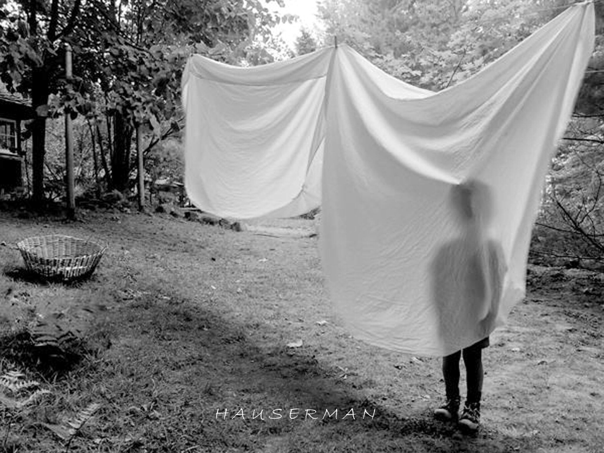 An image of a child standing behind white fabric draped on an outdoor clothesline.