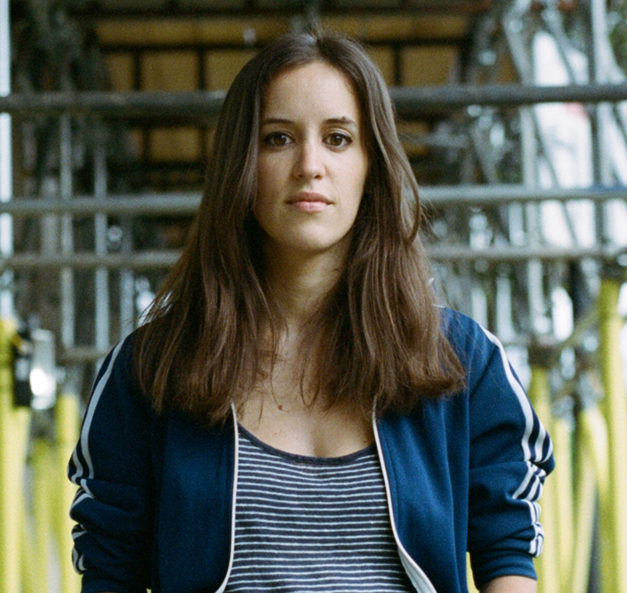 A portrait of a person standing in front of a metal structure.
