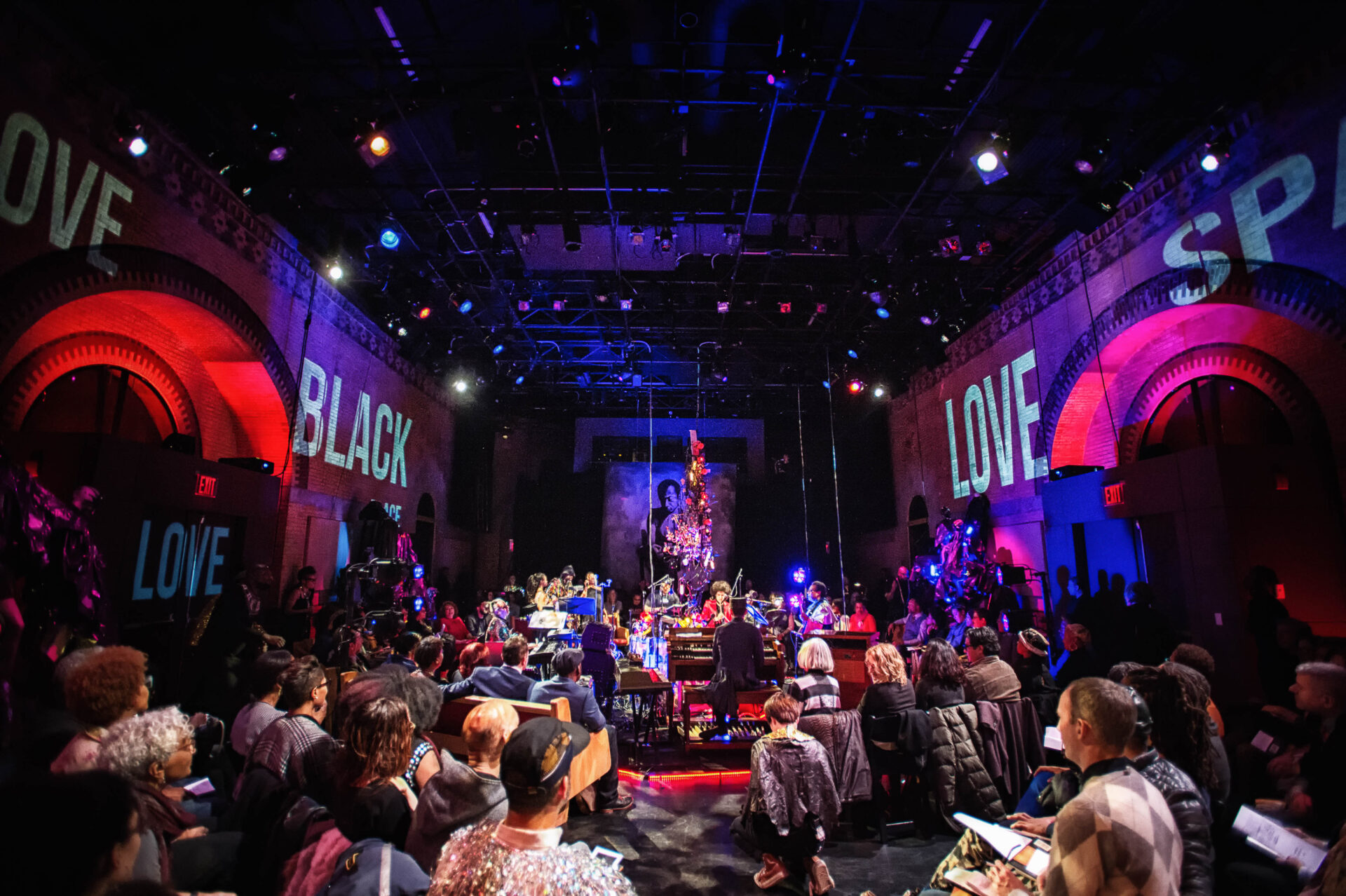A crowd of people with purple and red digital banners that read Black Love