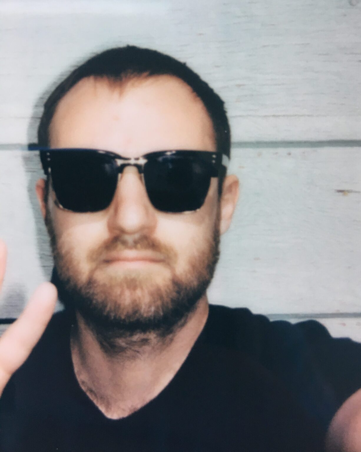 A portrait of a person in sunglasses against a light background.