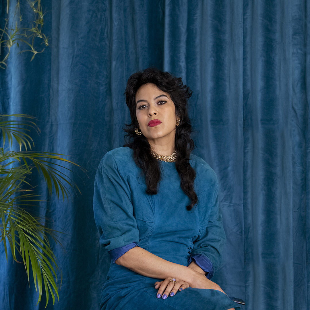 A portrait of a person against a blue fabric background.