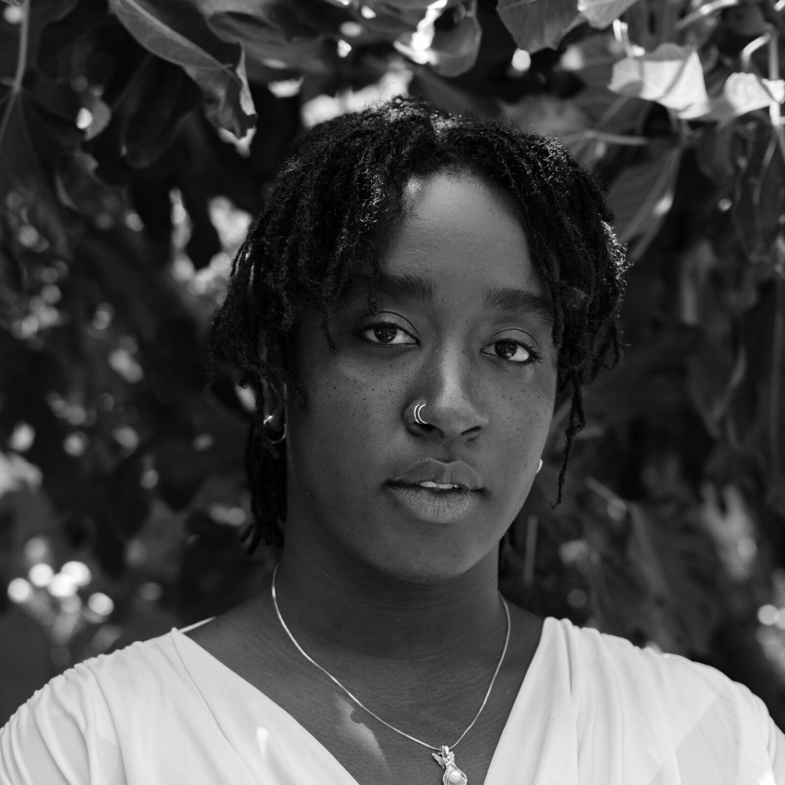 A portrait of a person standing in front of a leafy background.