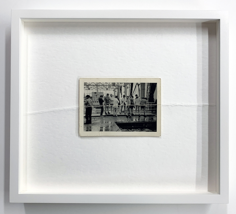 Photograph in a frame, a crease running horizontally across the photo and matte.