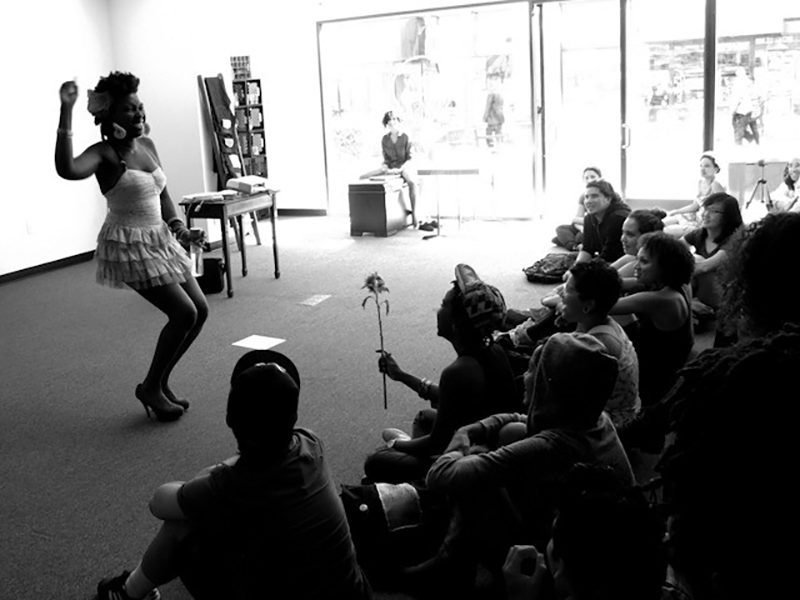 A black and white photo of a Black person performing in front of an audience.