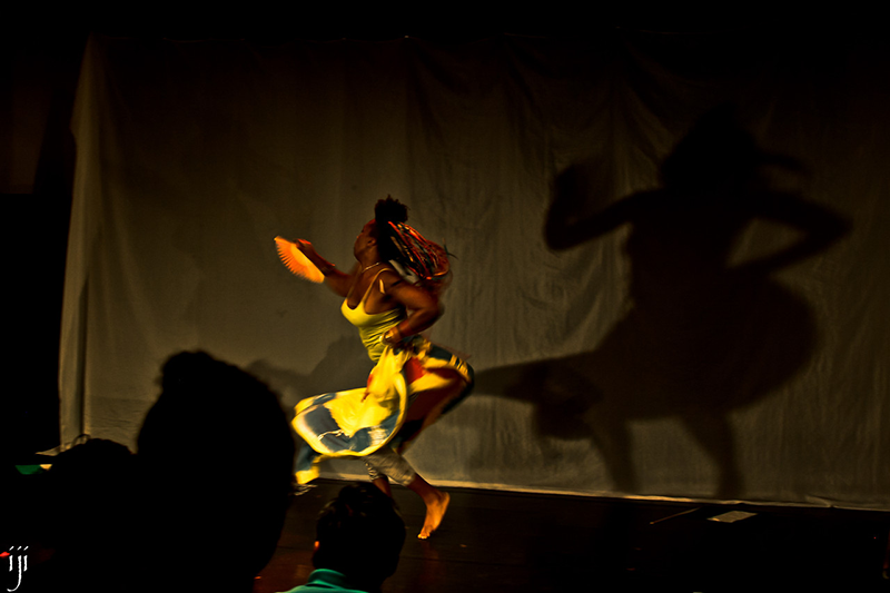 A Black person in a twirling dress performs on a stage.