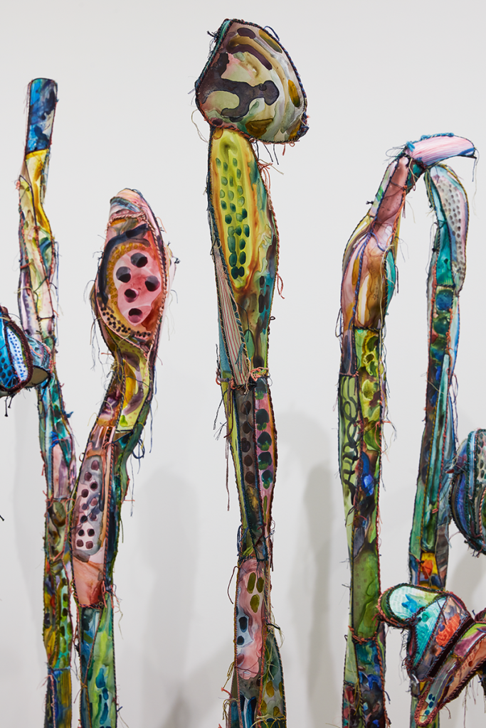 A group of colorful sculptural forms resembling freestanding vertical sticks or plant growths..