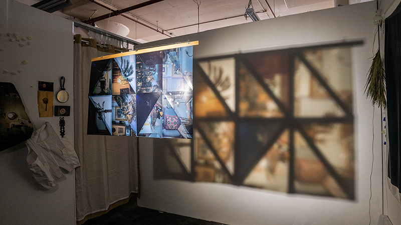 A set of collaged images hanging in a space with light projecting through them, casting larger projected images on the wall behind.