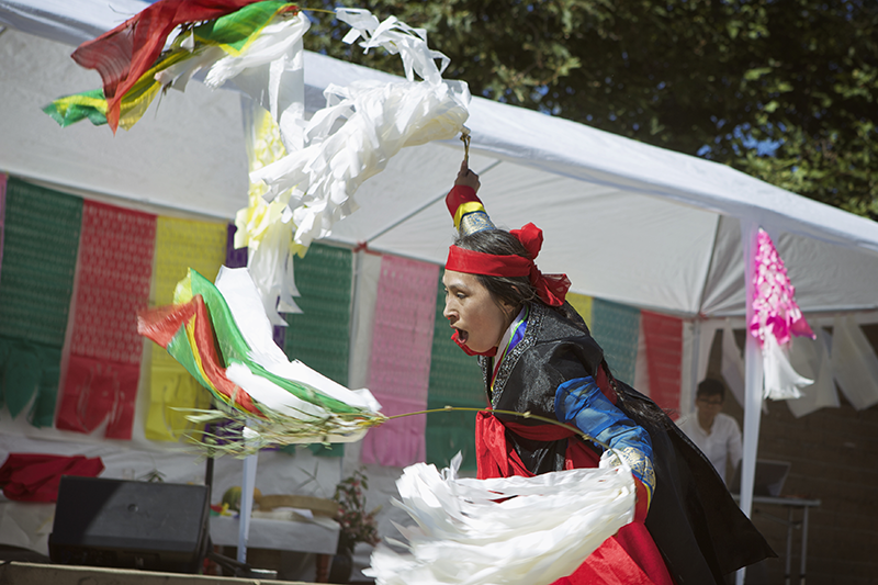 a person is vibrant red and black dress spins while holding multi-colored cut paper flags