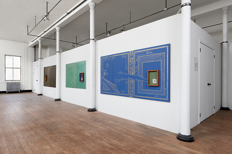installation of artworks in a long room, including a wall piece of painted blue