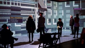 People standing in a drak room surrounded by projections of animated, abstract world