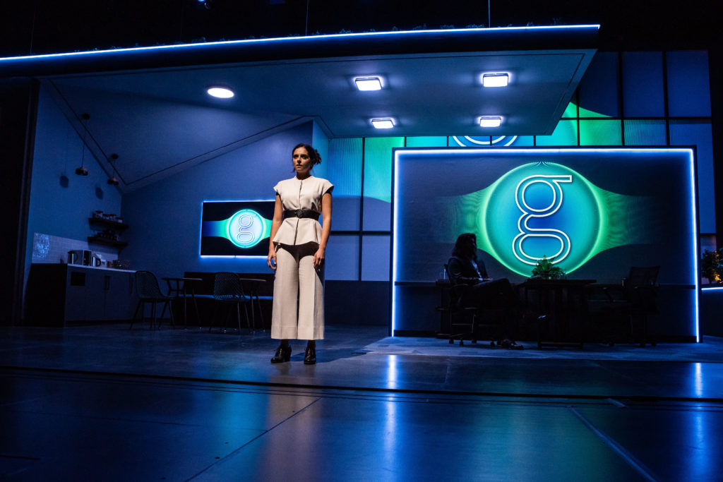 person standing on a stage lit with blue and green