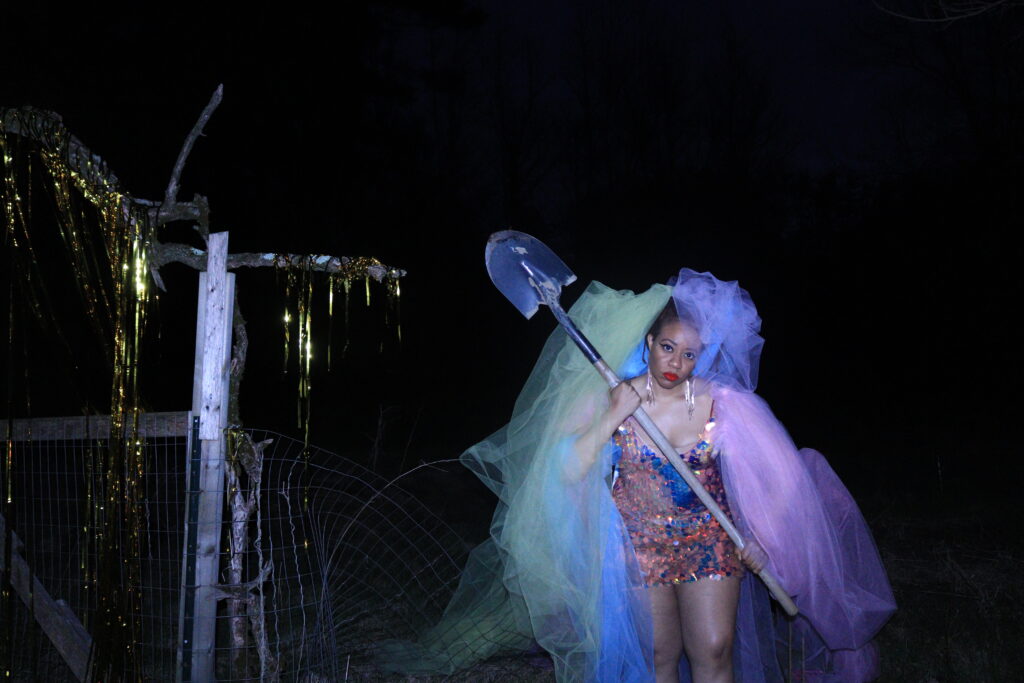 Ayana in tule outside at night with a shovel