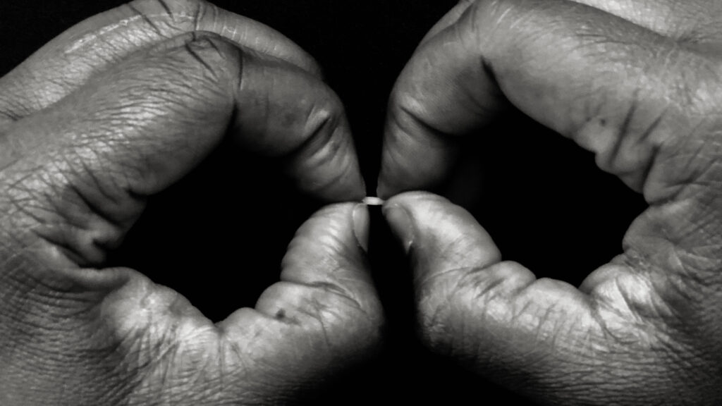 A black and white photo of two hands holding a grain.