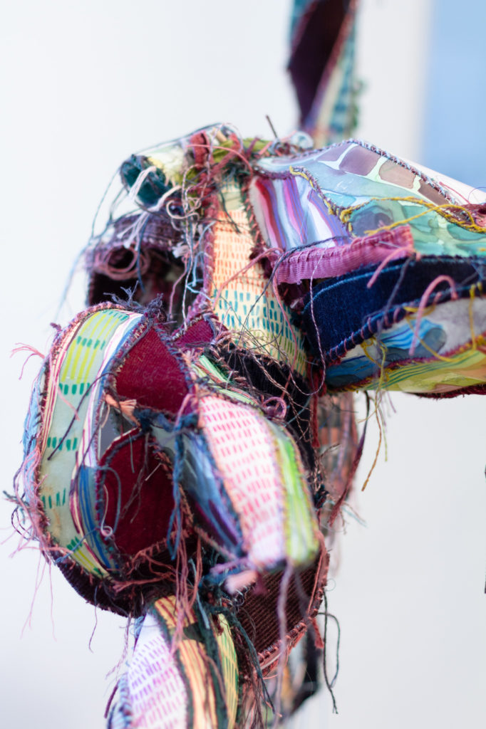 Closeup of sculpture in multiple colors with dangling thread