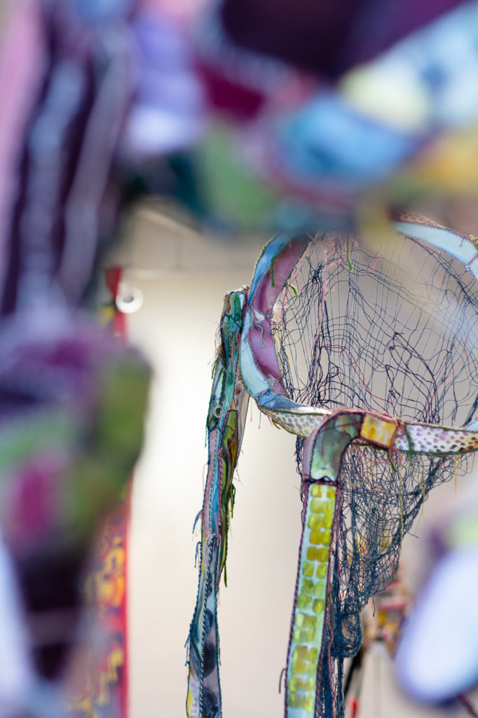 Closeup of sculpture in multiple colors with dangling thread and net