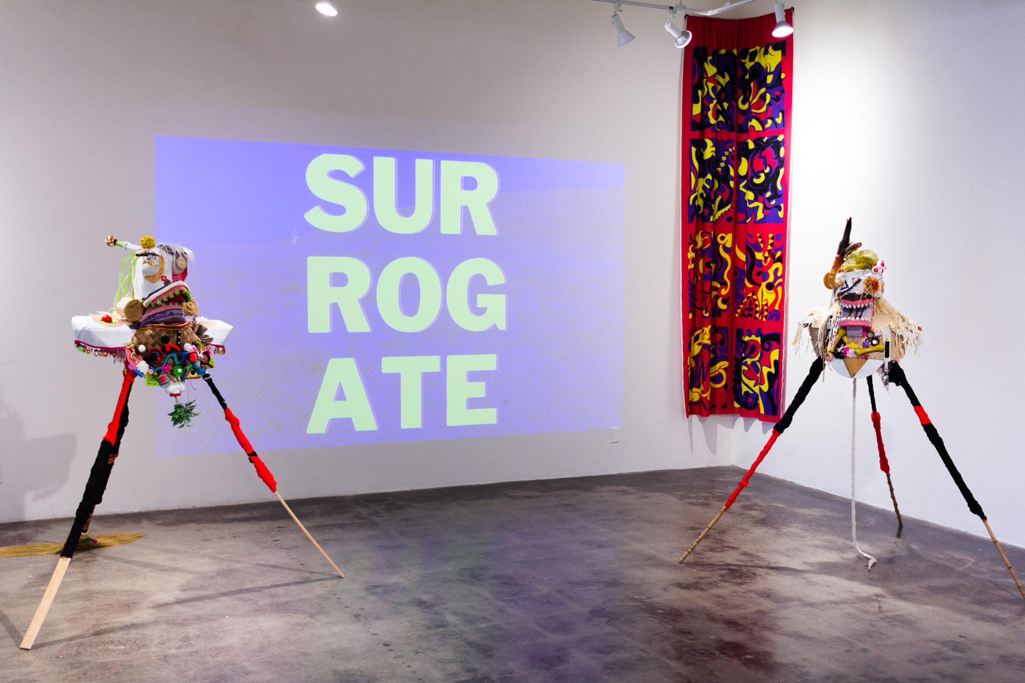 Sculptures beside a large projection with text readin g