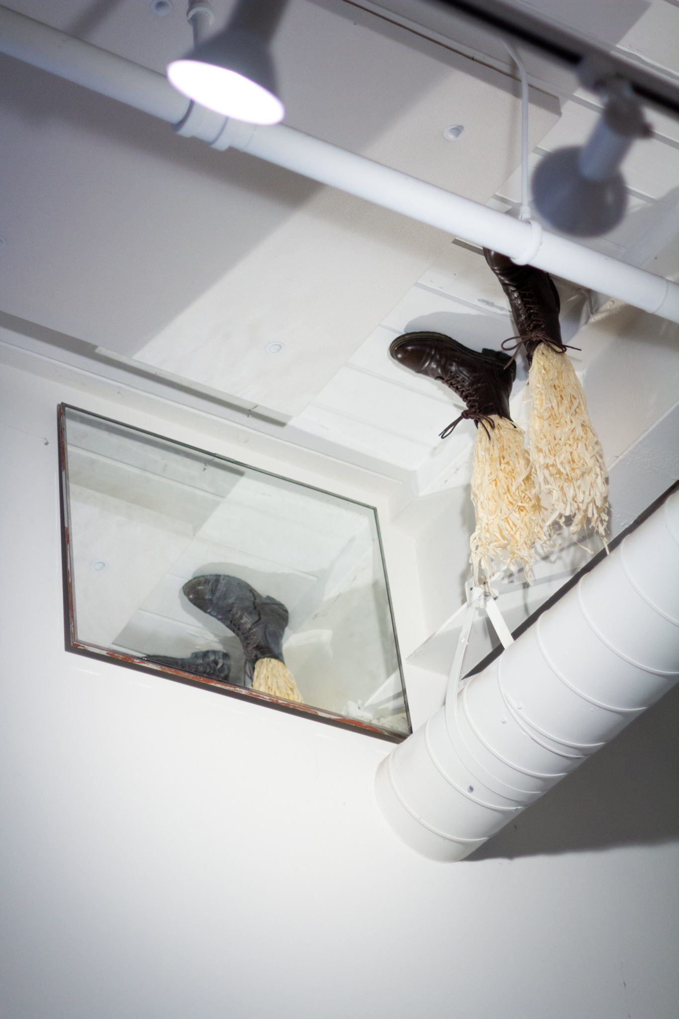 Boots attached ot the ceiling with straw where legs would be