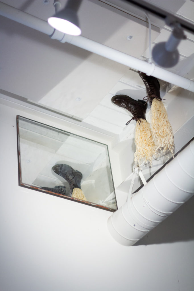 Boots attached ot the ceiling with straw where legs would be