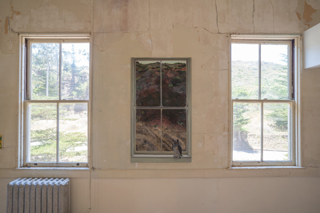 A painting of a window with an owl, hung on a wall between two windows