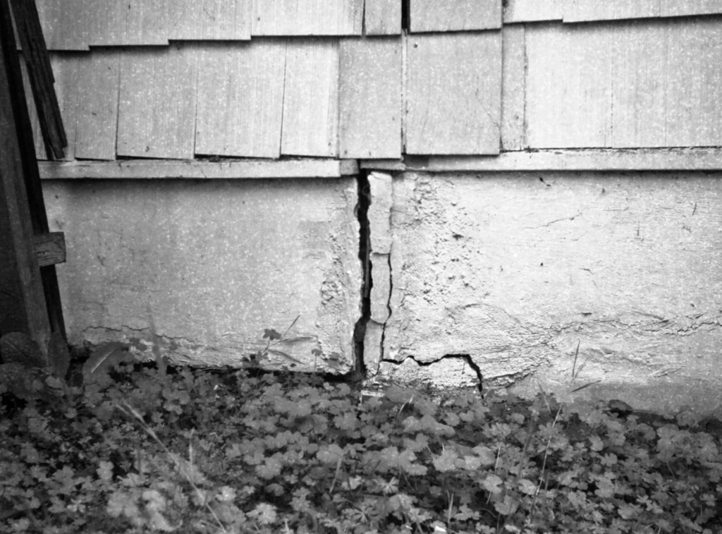 Black and white photo of a house foundation with a vertical crack.