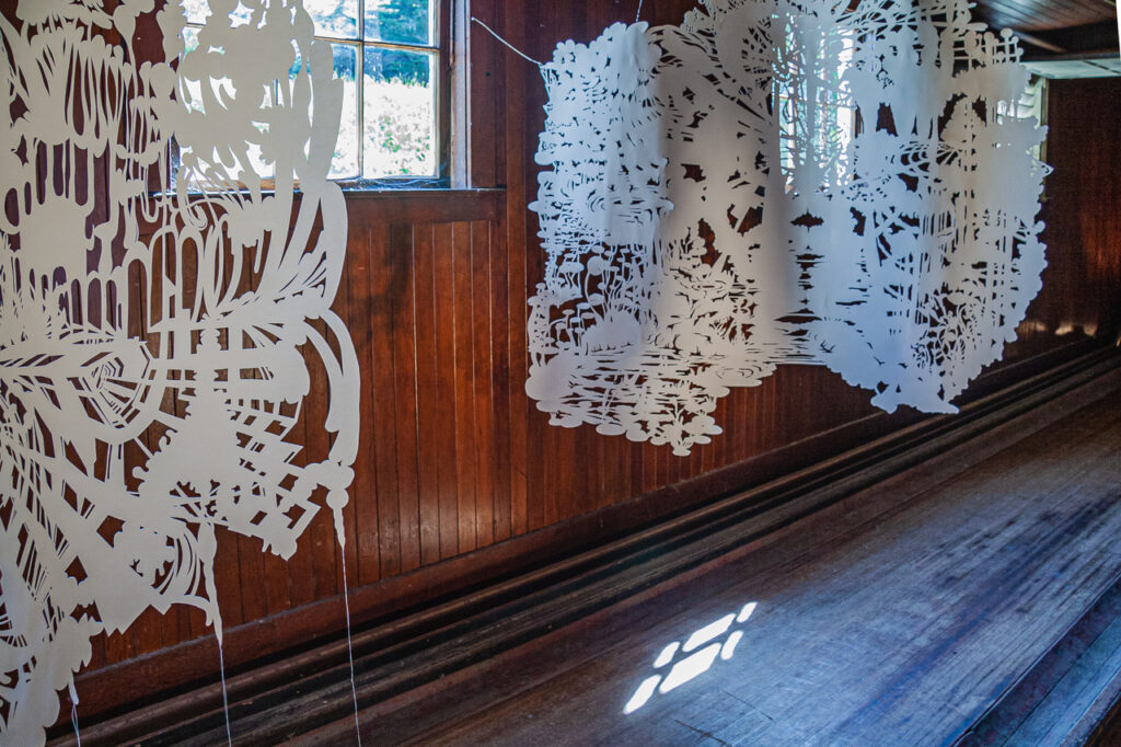 Intricate cut-paper objects hanging over a bowling lane