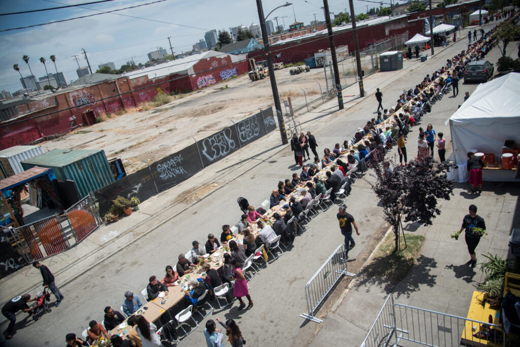 An aerial photo of people sitting at a very long table set up in a city street