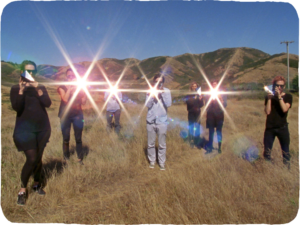 A group of people with bright stars (a visual phenomenon made with reflected light) in front of their faces.