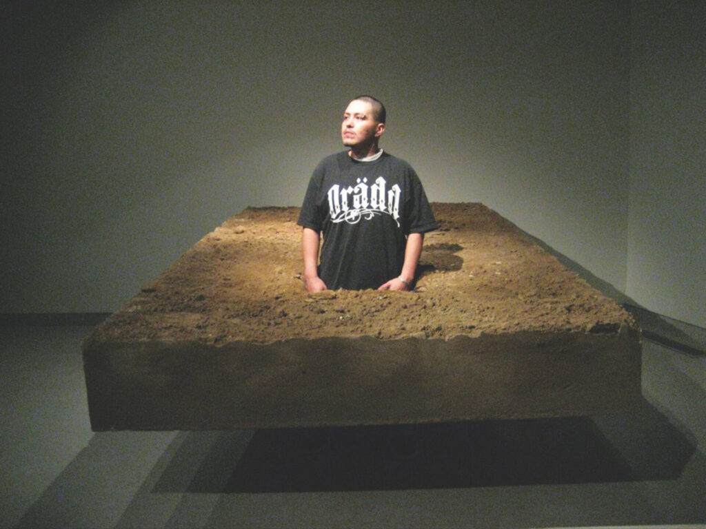 A person standing in a large slab of soil that appears to be floating above the floor.