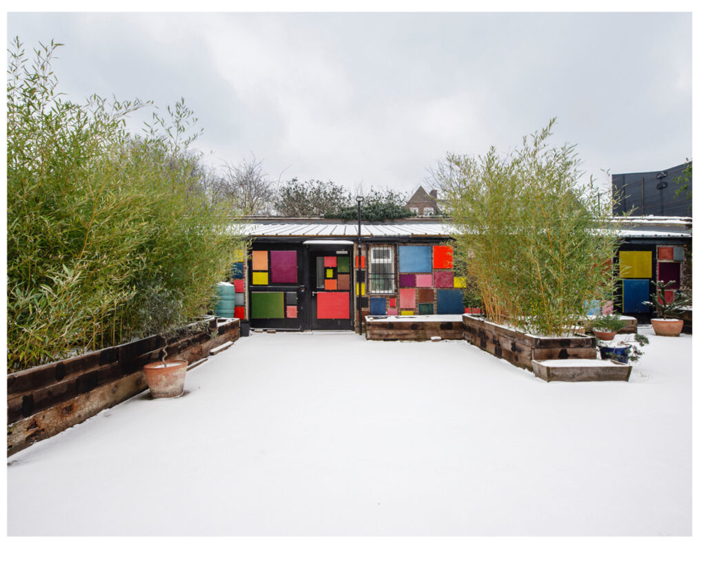 A low building covered with rectangular monochrome paintings in various colors.