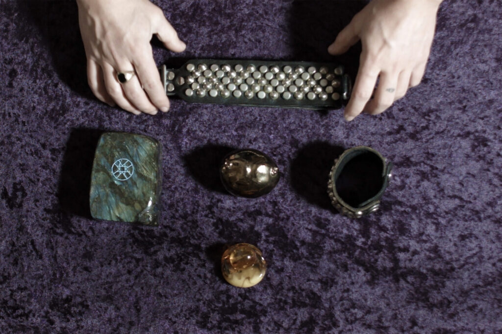 A pair of hands arranging objects on purple velvet