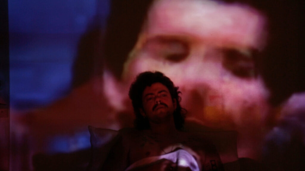 A person sitting infront of a video projection of themself