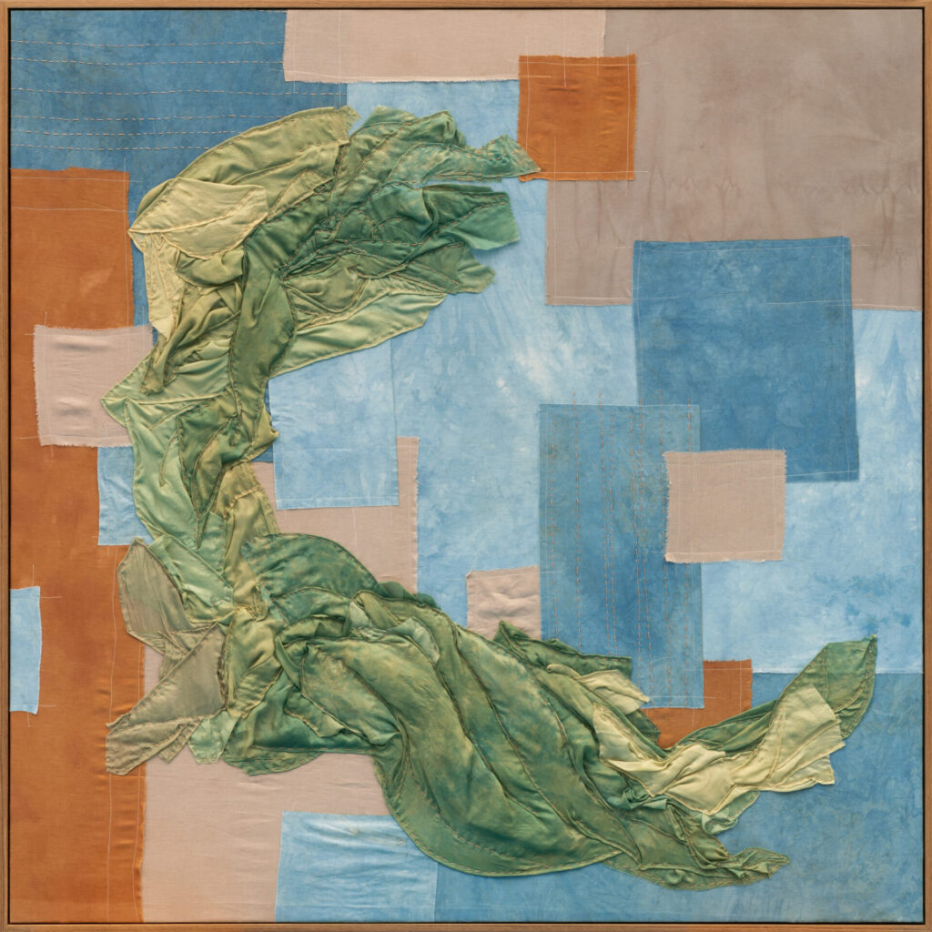 Quilted fabric: A green swirling form over rectangular swaths o fblue and orange
