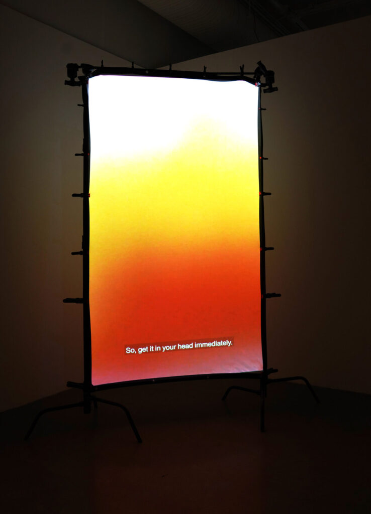 A projection on a hanging screen with a white to red gradient, and text that reads 