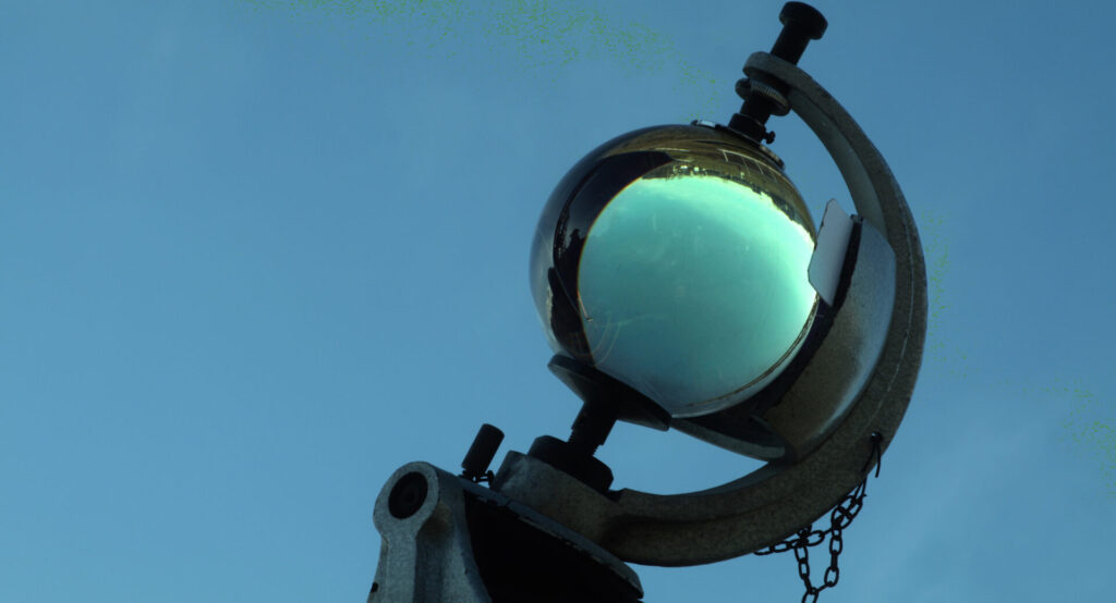 An image of a large glass sphere held in an apparatus against a blue background