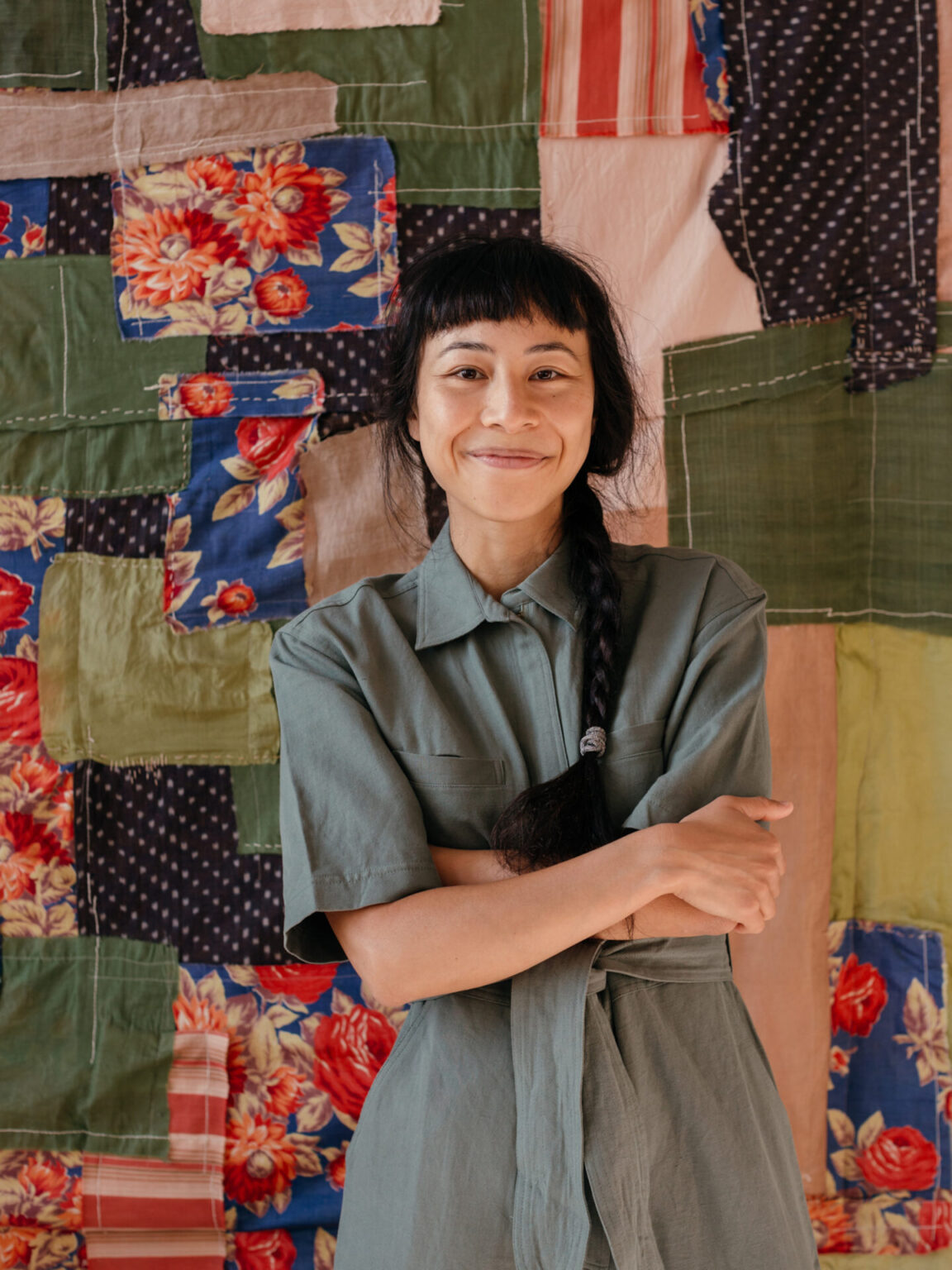 Portrait of Megumi Shauna Arai standing in front of a quilt