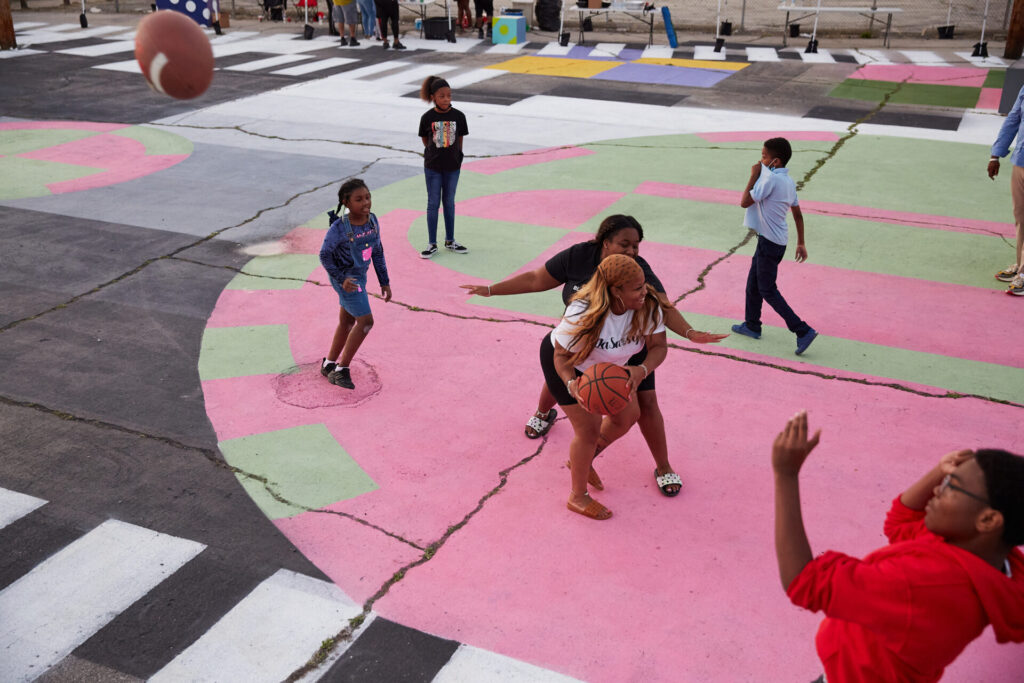 People playing basketball on a colorful pink and green basketball court