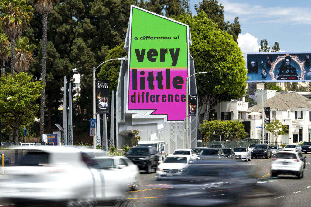 A large, irregular shaped digital billboard reads 