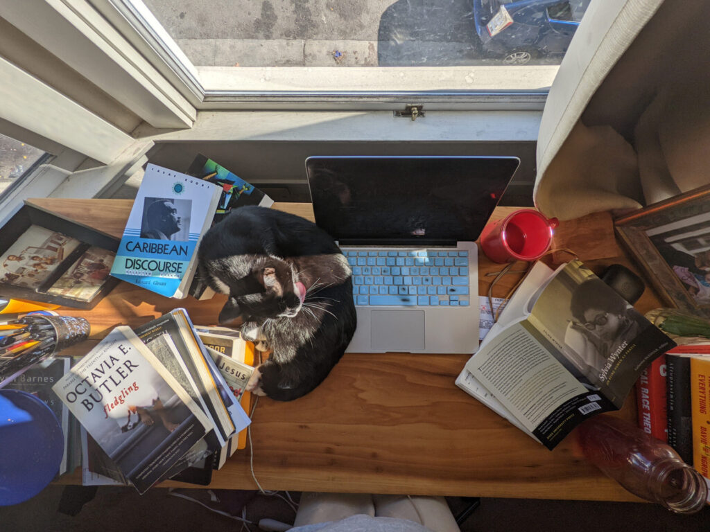 A cluttered desk with laptop and other things