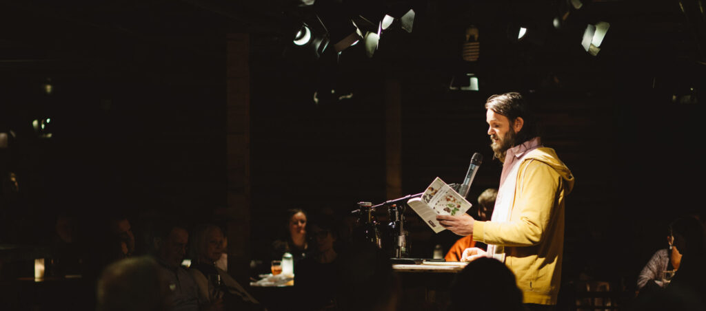 A photo of a person standing at a lecturn reading from a book