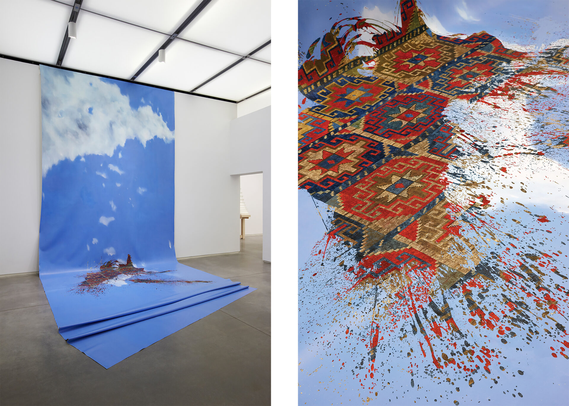 A painting or image of blue sky and clouds hanging from a wall draped onto the floor; a splattering of patterned red and blue like a rug or tilework is at the point of wall and floor meeting.